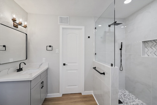 bathroom featuring tiled shower, hardwood / wood-style floors, and vanity