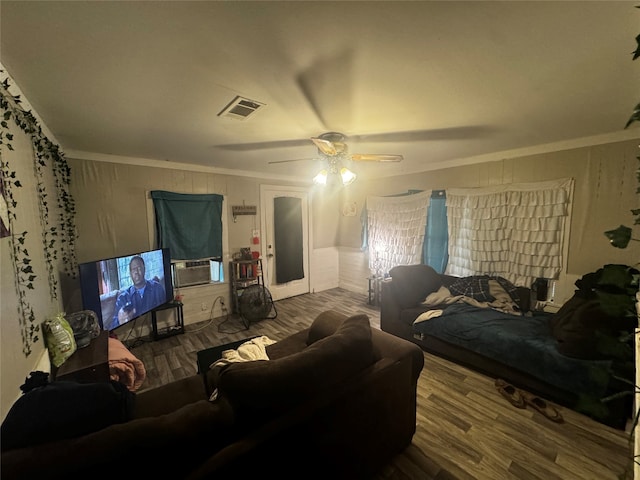 living room featuring cooling unit, ceiling fan, wood-type flooring, and ornamental molding