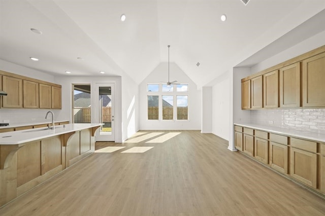 kitchen featuring decorative backsplash, sink, decorative light fixtures, light hardwood / wood-style flooring, and a breakfast bar area