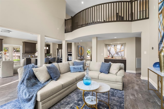 living room with dark hardwood / wood-style floors and a towering ceiling