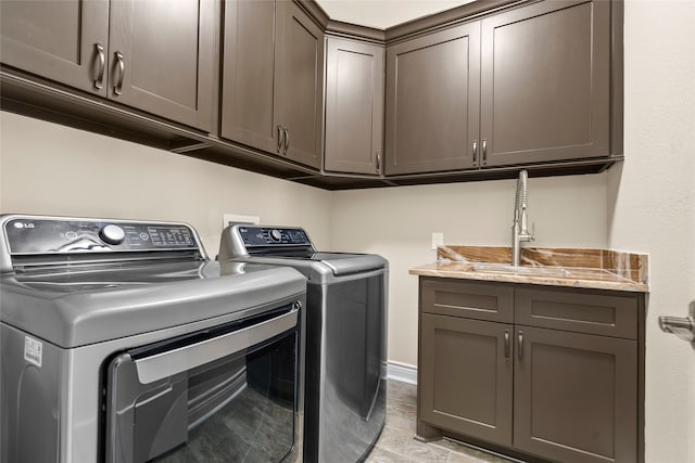 clothes washing area featuring washing machine and dryer, sink, and cabinets