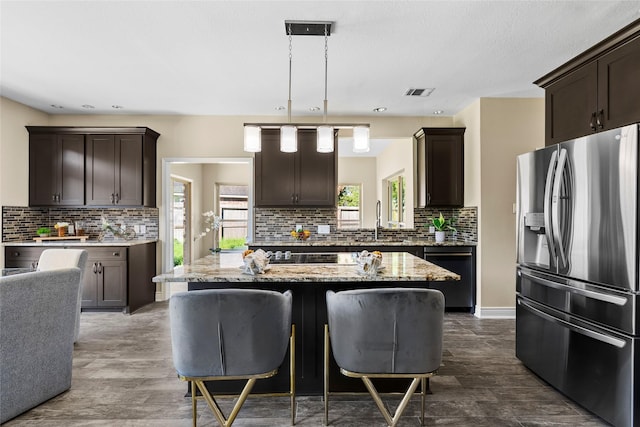 kitchen featuring pendant lighting, a center island, stainless steel fridge, and light stone countertops