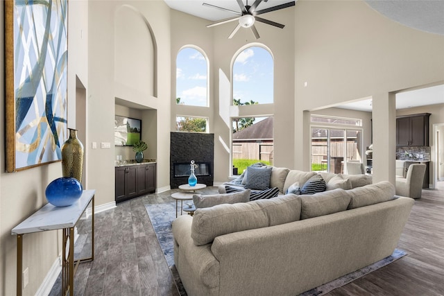 living room featuring a towering ceiling, light hardwood / wood-style flooring, and ceiling fan