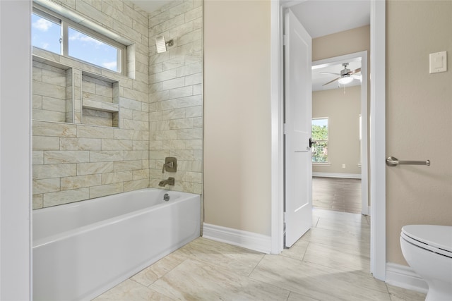 bathroom featuring toilet, plenty of natural light, and tiled shower / bath