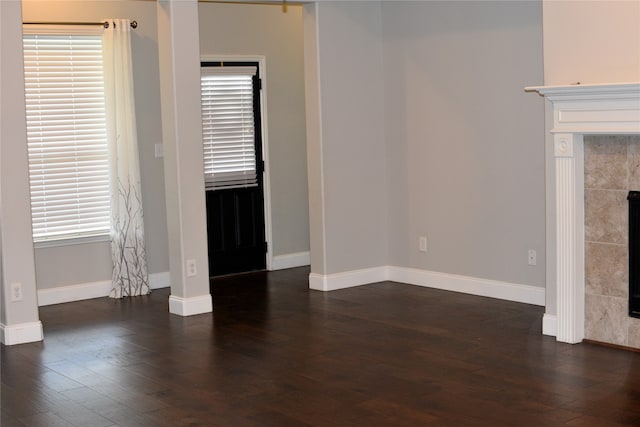 unfurnished living room featuring a tiled fireplace and dark wood-type flooring