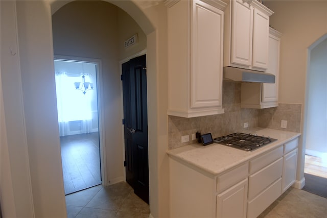 kitchen with stainless steel gas stovetop, white cabinetry, light hardwood / wood-style flooring, and tasteful backsplash