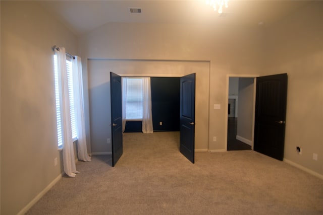 unfurnished bedroom with lofted ceiling and light carpet