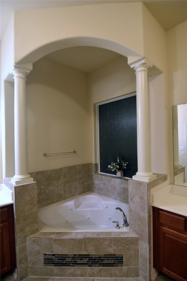 bathroom with a relaxing tiled tub, vanity, and ornate columns