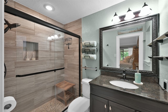 bathroom featuring toilet, a shower with door, a textured ceiling, and vanity