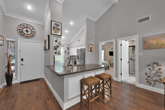 kitchen with stainless steel fridge with ice dispenser, dark wood-type flooring, kitchen peninsula, high vaulted ceiling, and white cabinets