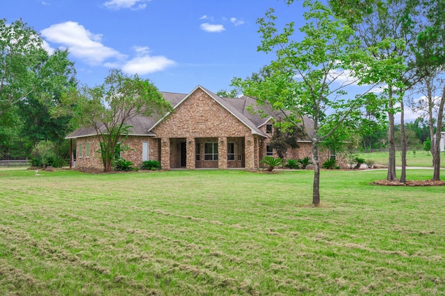 view of front of home featuring stone siding, roof with shingles, and a front lawn