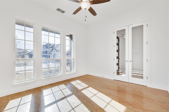 unfurnished room featuring light wood finished floors, visible vents, baseboards, french doors, and a ceiling fan