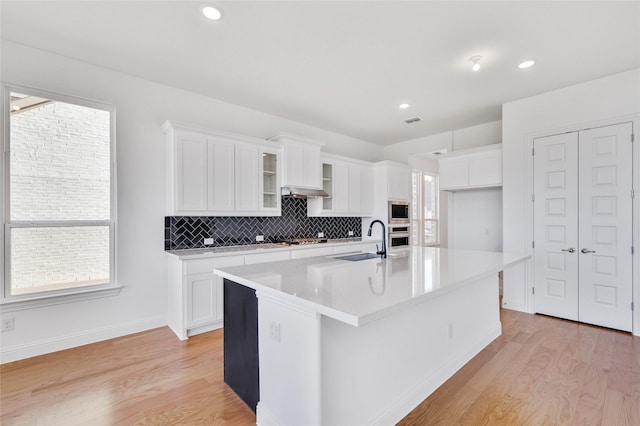 kitchen with a sink, light wood-style floors, appliances with stainless steel finishes, and white cabinets