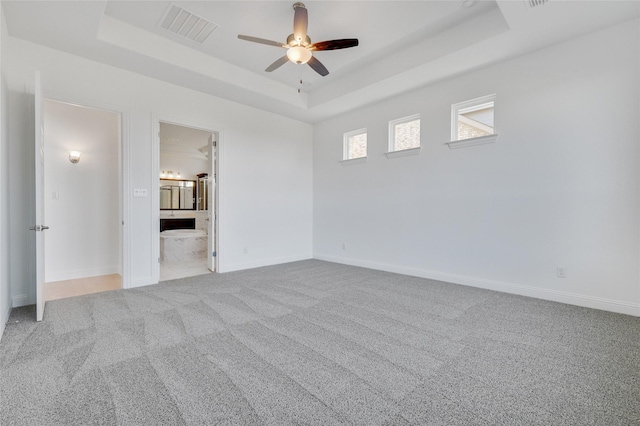 unfurnished bedroom with visible vents, baseboards, carpet, and a tray ceiling