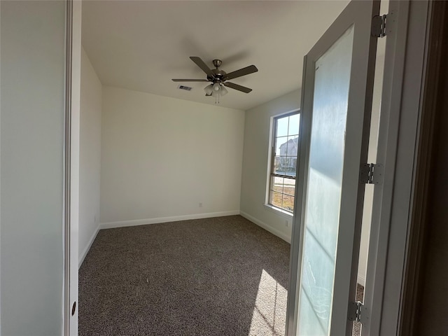 carpeted empty room with visible vents, a ceiling fan, and baseboards