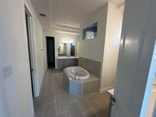 bathroom featuring baseboards, visible vents, vanity, and a garden tub