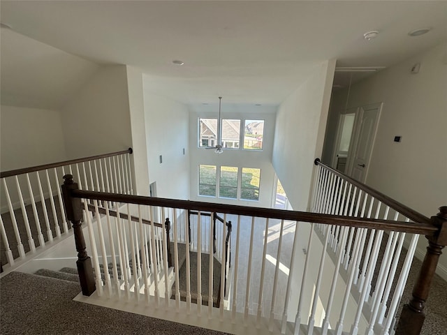 hallway featuring attic access and a towering ceiling