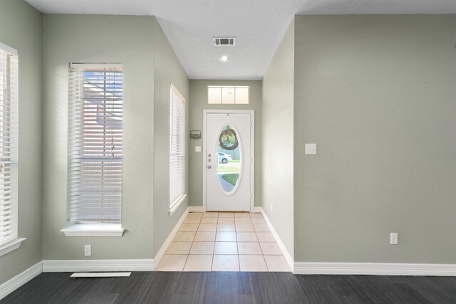 foyer entrance with a textured ceiling and light hardwood / wood-style floors