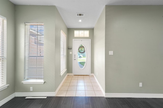 tiled entrance foyer with visible vents and baseboards