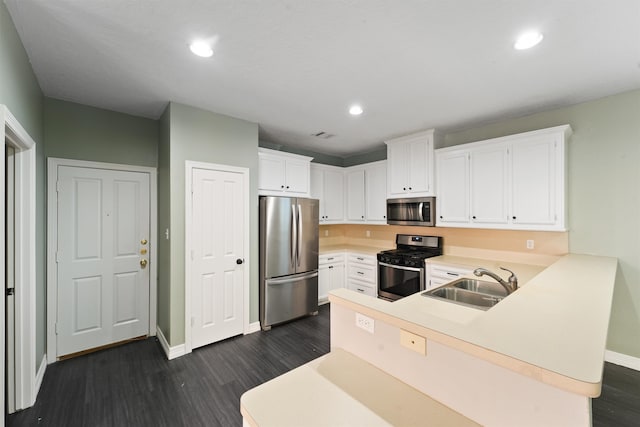 kitchen with stainless steel appliances, kitchen peninsula, sink, dark wood-type flooring, and white cabinets