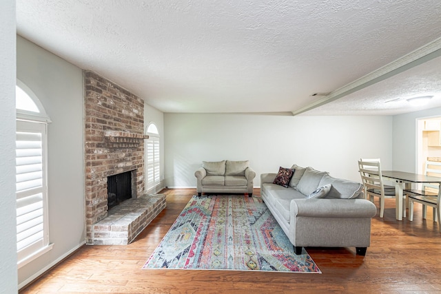 living room with a brick fireplace, wood-type flooring, and a textured ceiling