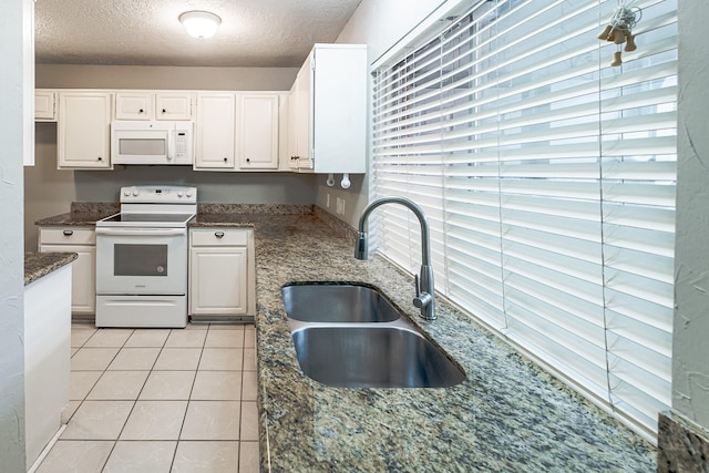 kitchen with white cabinetry, sink, a textured ceiling, and white appliances