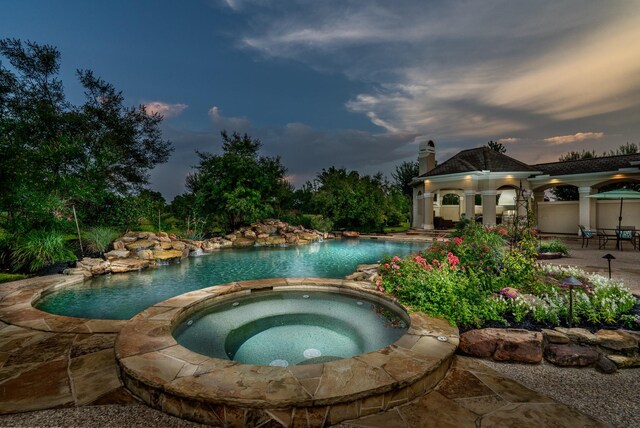 pool at dusk featuring a patio, an in ground hot tub, and a gazebo