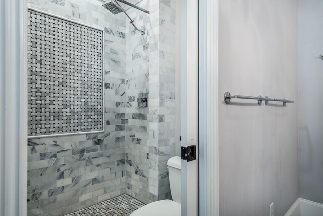 bathroom featuring toilet and a tile shower