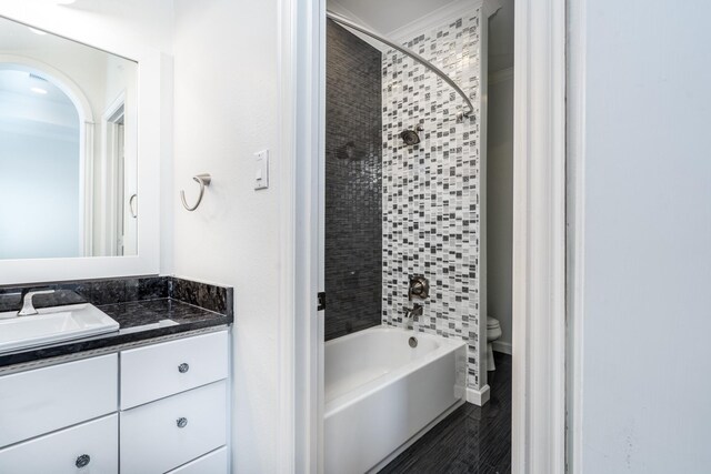 full bathroom featuring crown molding, hardwood / wood-style floors, toilet, tiled shower / bath combo, and vanity