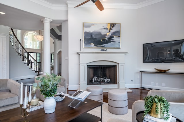 living room featuring ceiling fan, hardwood / wood-style flooring, crown molding, and ornate columns