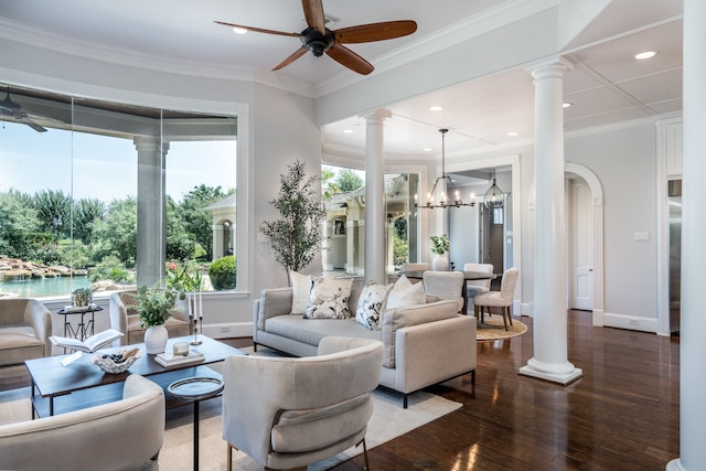 living room featuring ornamental molding, ceiling fan with notable chandelier, dark hardwood / wood-style flooring, and ornate columns