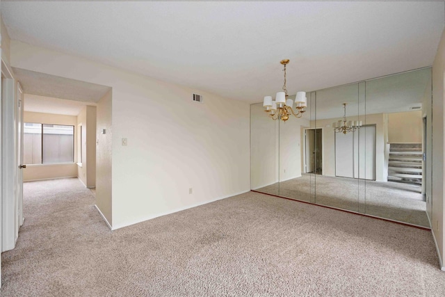 carpeted empty room with a chandelier