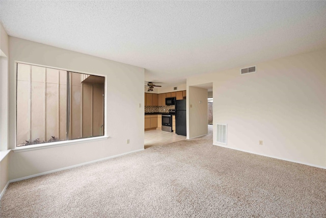 unfurnished living room with light colored carpet and a textured ceiling