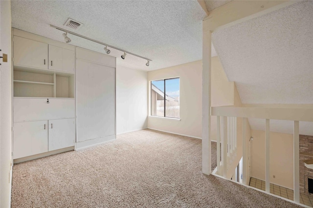 additional living space featuring light carpet, a textured ceiling, a brick fireplace, and vaulted ceiling