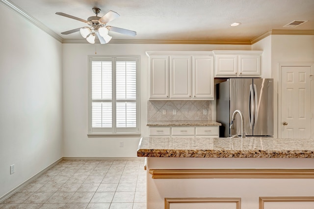 kitchen featuring tasteful backsplash, crown molding, stainless steel refrigerator, white cabinetry, and ceiling fan