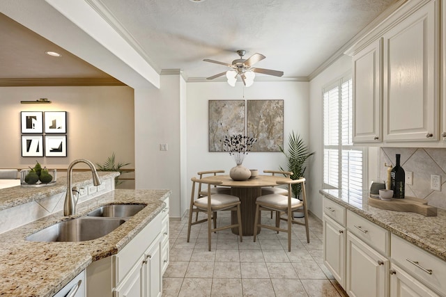 kitchen featuring light stone counters, ceiling fan, sink, and white cabinetry