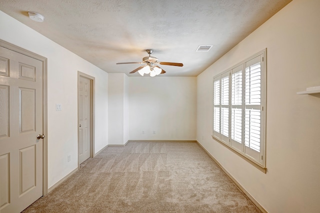 unfurnished room with a textured ceiling, light colored carpet, and ceiling fan