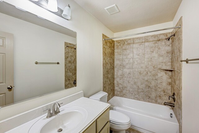 full bathroom with tiled shower / bath, vanity, toilet, and a textured ceiling