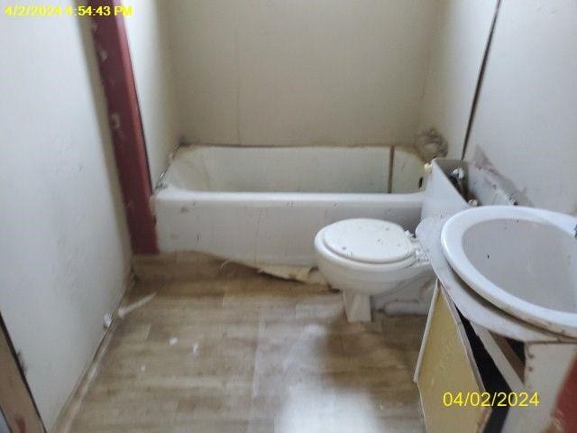 bathroom with a tub to relax in and toilet