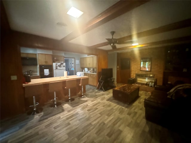 living room with bar area, ceiling fan, hardwood / wood-style flooring, and a fireplace