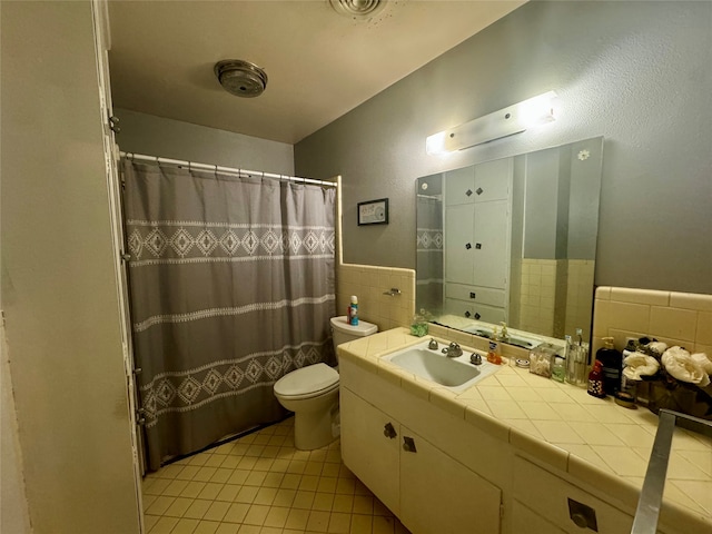 bathroom with vanity, walk in shower, tile walls, toilet, and tile patterned floors