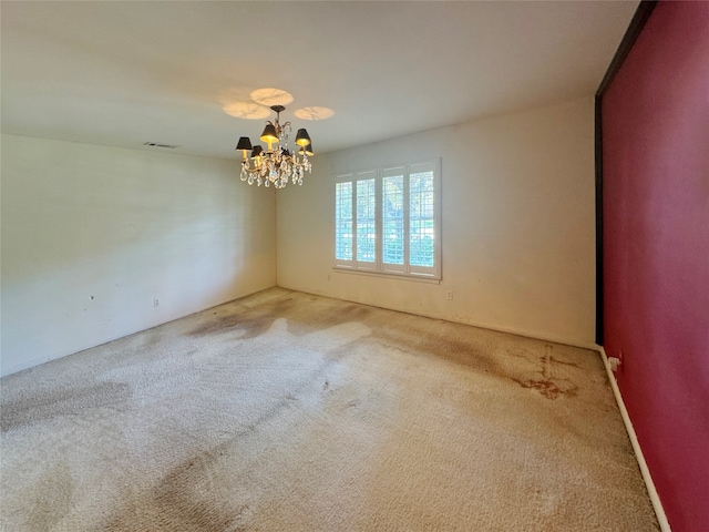 carpeted spare room featuring a notable chandelier