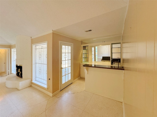 interior space featuring crown molding, a textured ceiling, and a brick fireplace