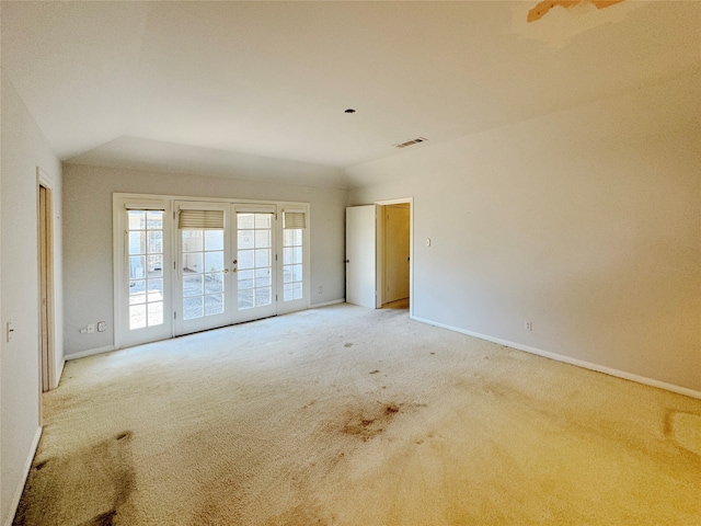 carpeted spare room with french doors and vaulted ceiling