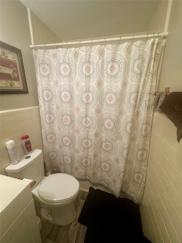 bathroom with vanity, toilet, a shower with curtain, and tile walls