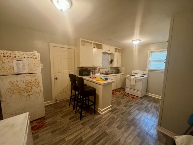 kitchen with white cabinets, white appliances, dark hardwood / wood-style flooring, kitchen peninsula, and a kitchen bar