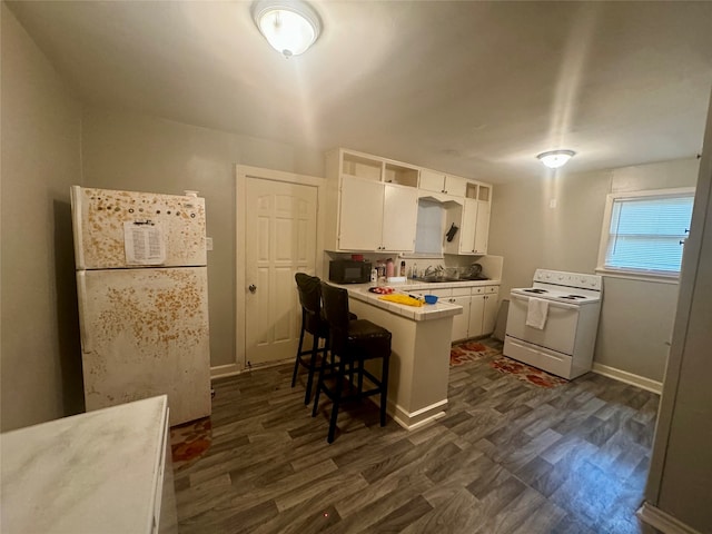 kitchen with white cabinetry, sink, white range with electric stovetop, kitchen peninsula, and a kitchen breakfast bar