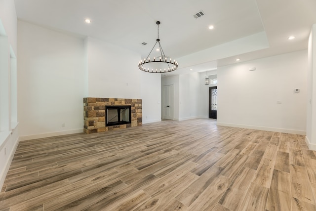 unfurnished living room featuring wood-type flooring and a stone fireplace