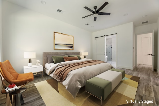 bedroom featuring a barn door, dark hardwood / wood-style floors, and ceiling fan