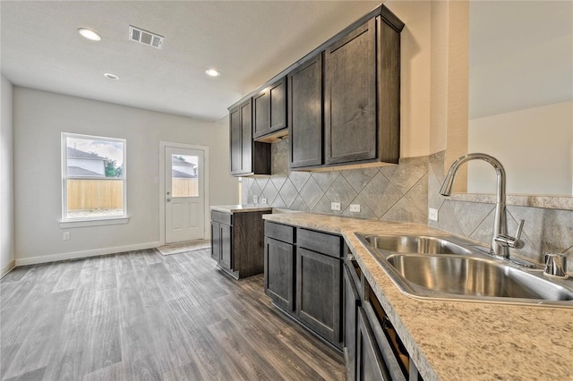 kitchen with dark brown cabinets, hardwood / wood-style flooring, sink, and decorative backsplash